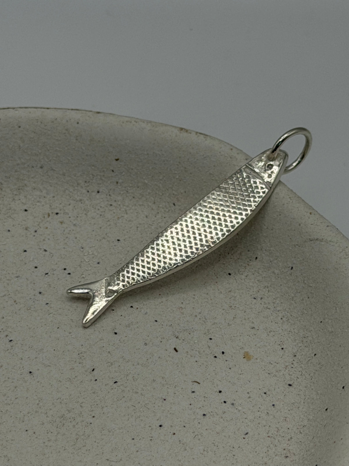 Handmade fine silver Love Lock charm featuring a handstamped fish design on a delicate, textured silver disc, finished with a beaded detail across the top.