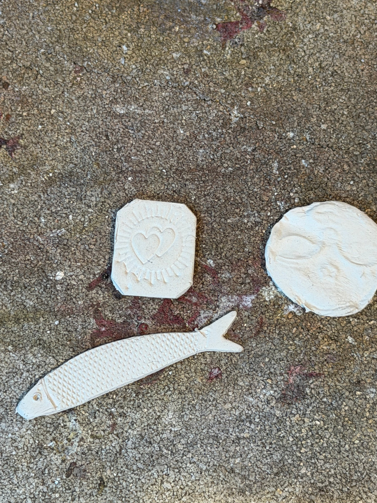 Unfired fine silver clay designs including a textured fish, heart motif and organic pendant shapes during a Wild One Metal Clay Play workshop