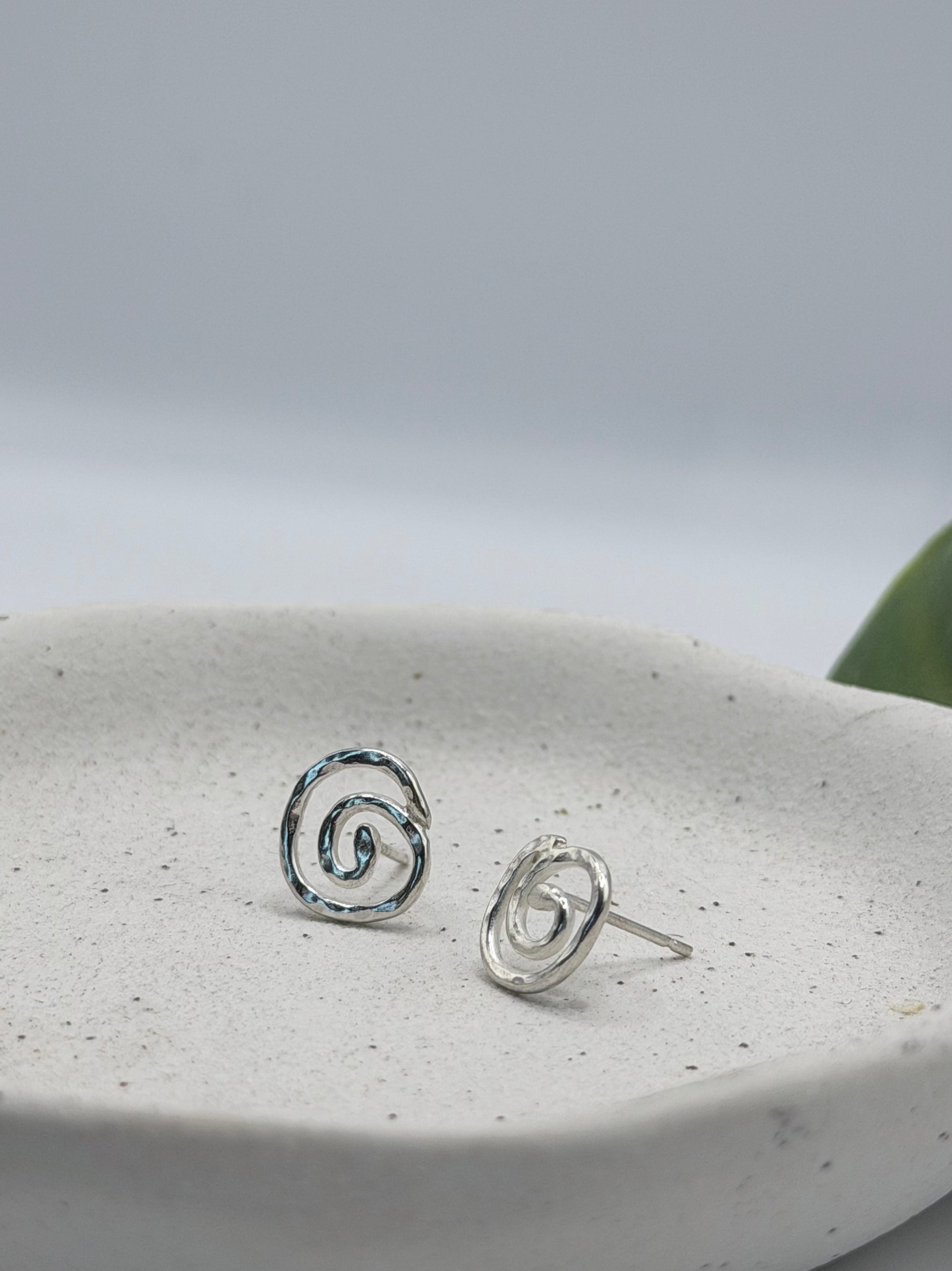 Handmade recycled sterling silver swirl stud earrings with organic spiral designs and a textured polished finish, crafted in small batches by independent Lincolnshire silversmith Wild One Jewellery.