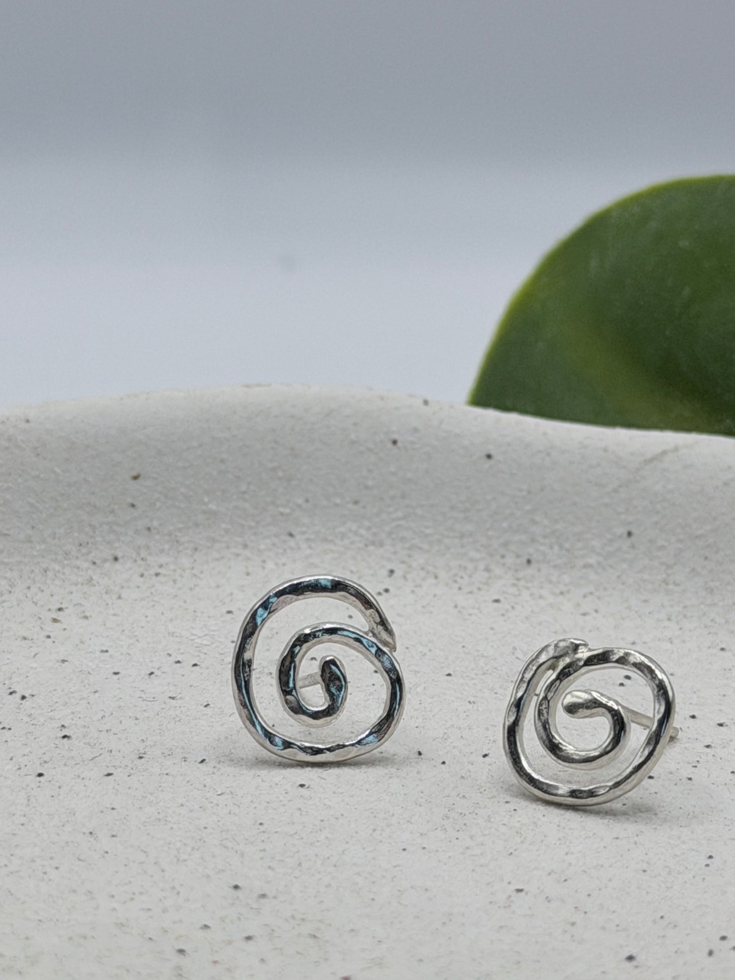 Handmade recycled sterling silver swirl stud earrings with organic spiral designs and a textured polished finish, crafted in small batches by independent Lincolnshire silversmith Wild One Jewellery.