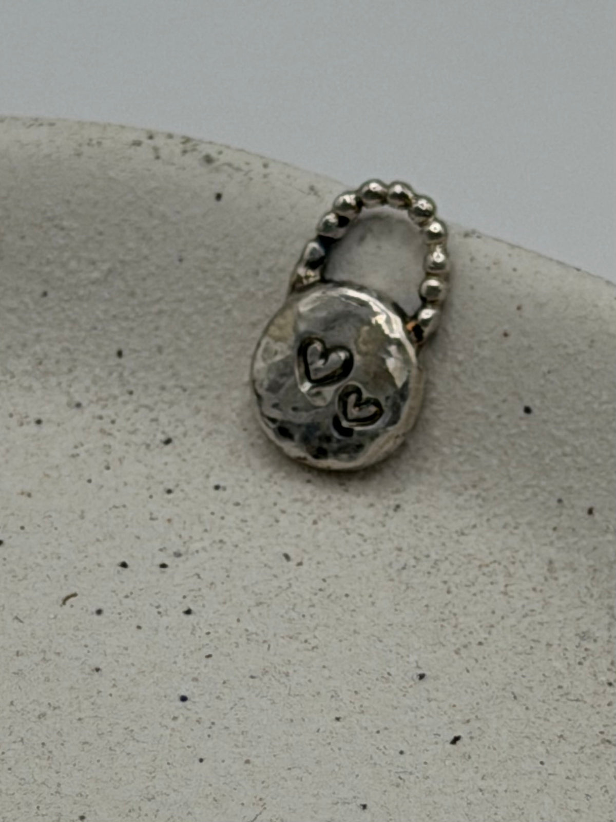 Handmade fine silver Love Lock charm featuring an organic, textured disc with softly rippled detail and a row of beaded silver detail.