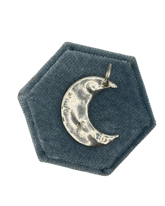 Handmade maxi crescent moon charm crafted from 999 fine silver metal clay, featuring an organic shape and textured finish on a dark green velvet jewellery display.