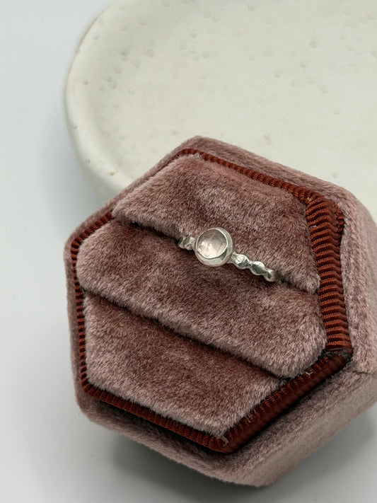 Mini faceted rose quartz ring with a pale pink gemstone set on a textured sterling silver pebble band.