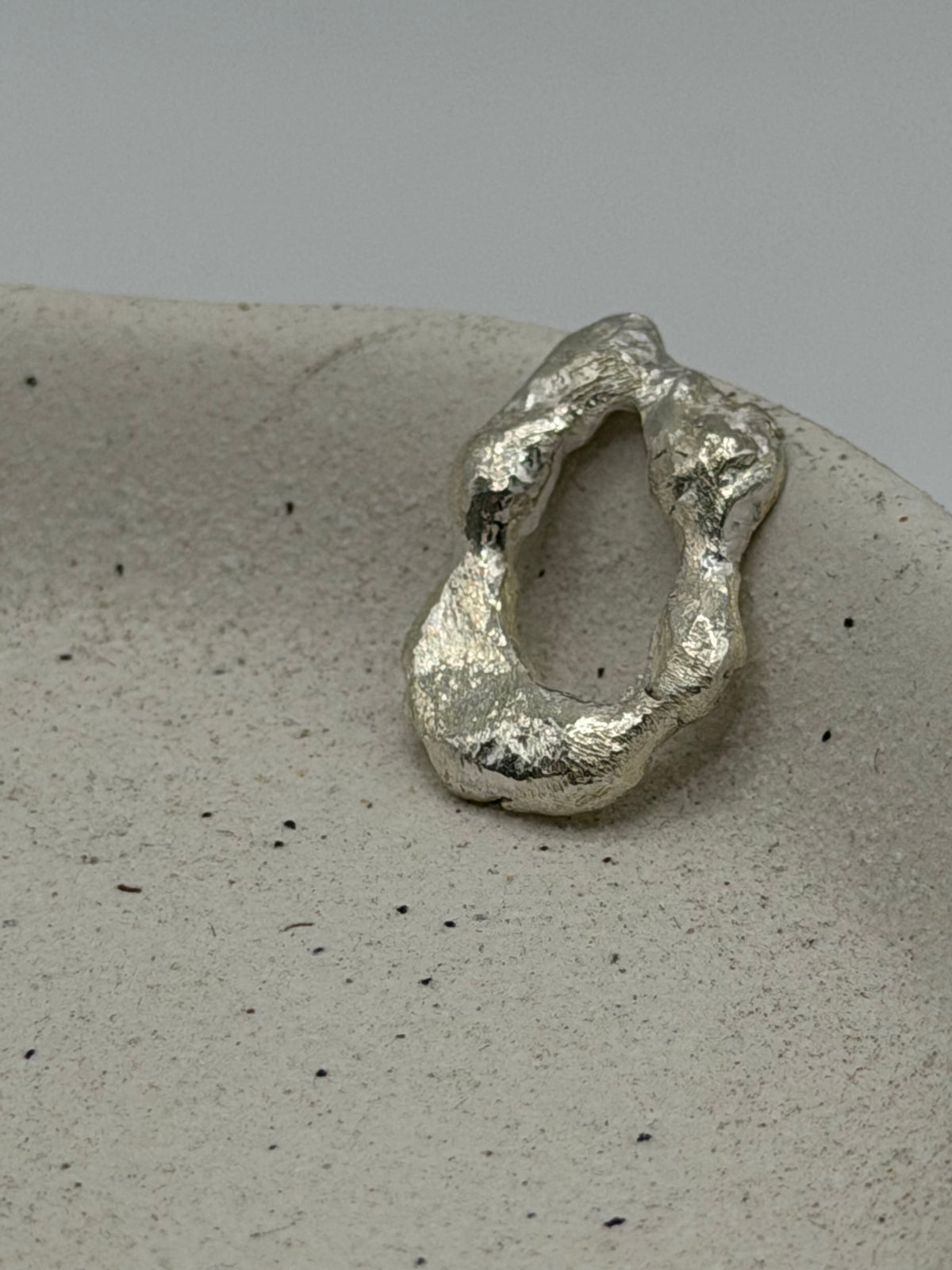 Handmade fine silver molten charm featuring an organic, textured disc with softly rippled detail and a row of beaded silver detail\.