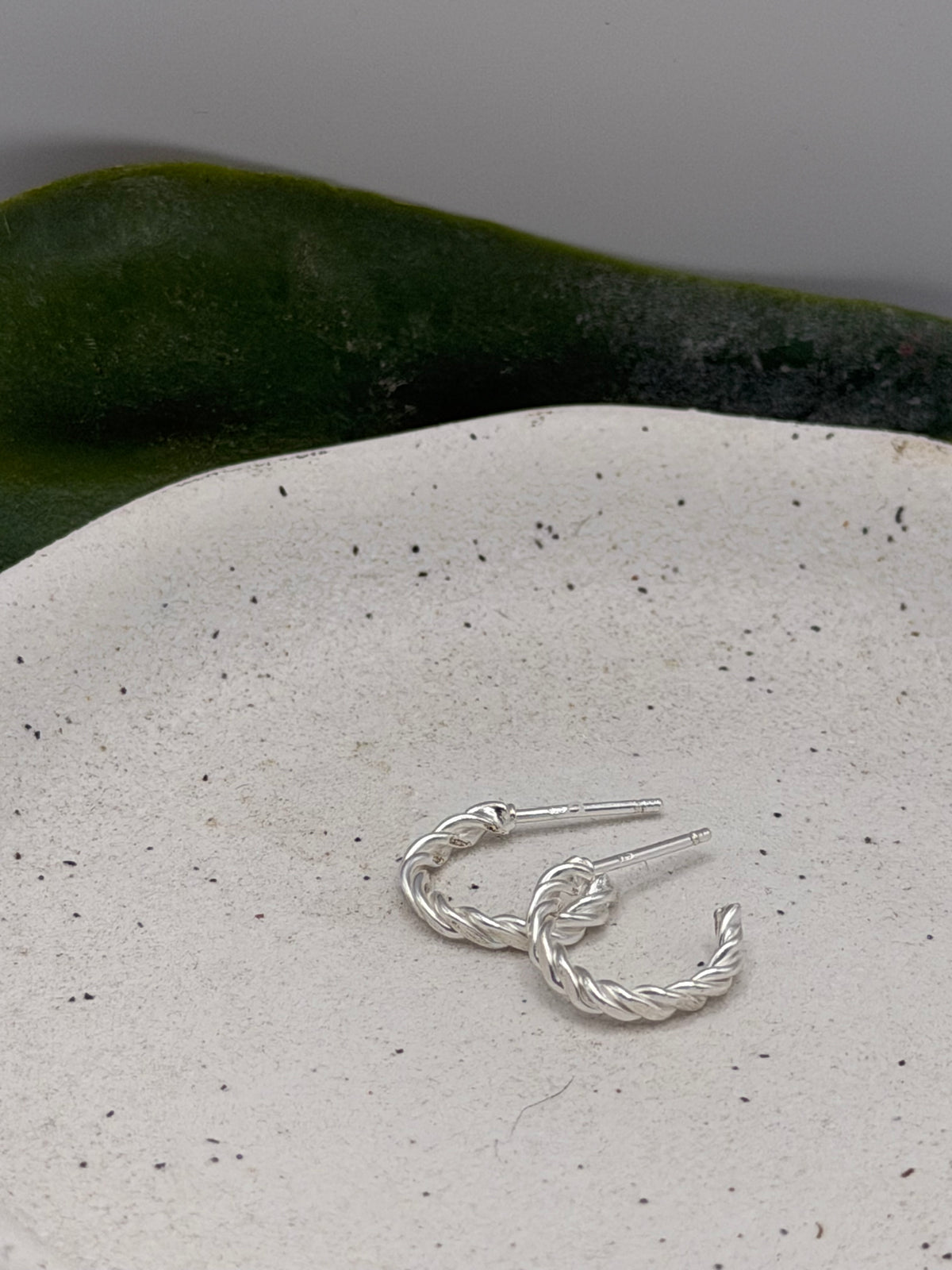 Side view of handmade recycled sterling silver rope hoops highlighting their sculptural twisted shape and open hoop design.