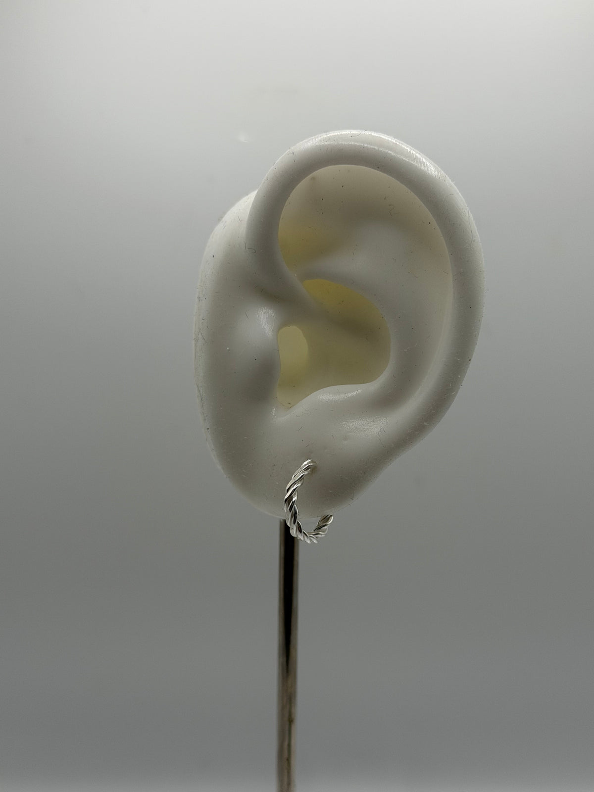 handmade recycled sterling silver rope hoops highlighting their sculptural twisted shape and open hoop design.