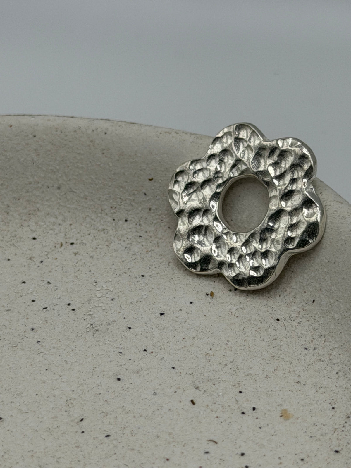 Handmade fine silver six petal flower charm featuring a handstamped floral design on a textured organic disc with beaded silver detail\.