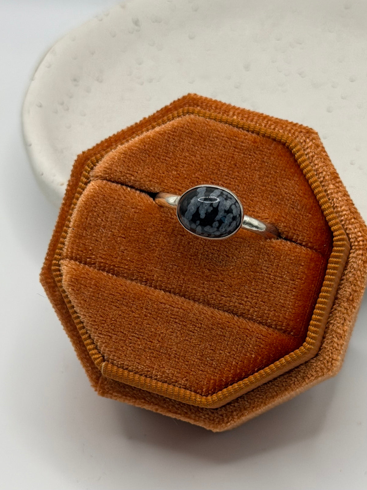 One-of-a-kind mini faceted snowflake obsidian ring from the Stone + Silver collection by Wild One Jewellery, featuring an oval black gemstone with pale snowflake-like markings set on a textured sterling silver pebble band.