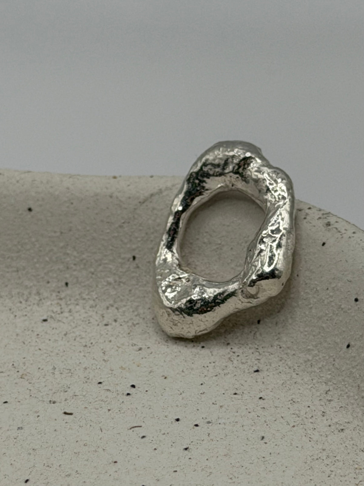 Handmade fine silver molten charm featuring an organic, textured disc with softly rippled detail and a row of beaded silver detail\.