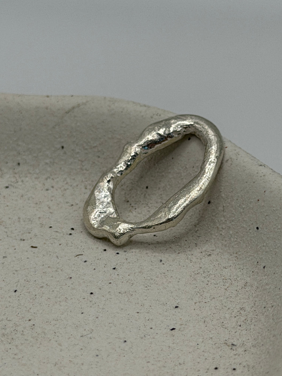 Handmade fine silver molten charm featuring an organic, textured disc with softly rippled detail and a row of beaded silver detail\.